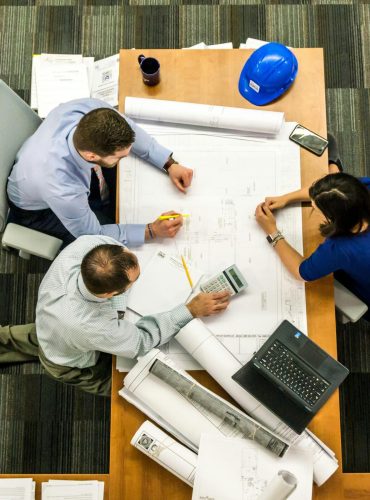 Top view of a team working on construction plans in an office setting.